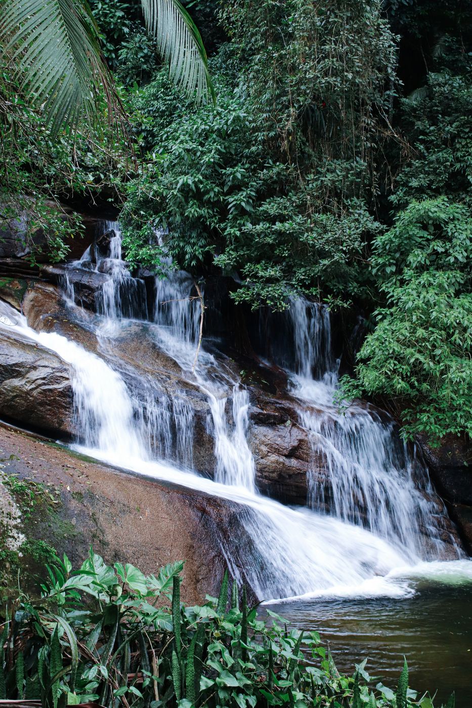 Wasserfall mit mehreren Stufen zwischen Felsen und Wald