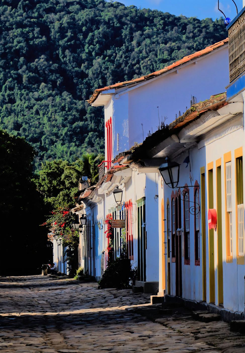 Rue pavée du centre historique de Paraty, avec de grandes maisons blanches aux portes colorées