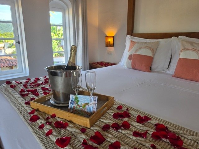 Cama com pétalas de rosa, Chandon no balde de gelo e um cartão escrito à mão